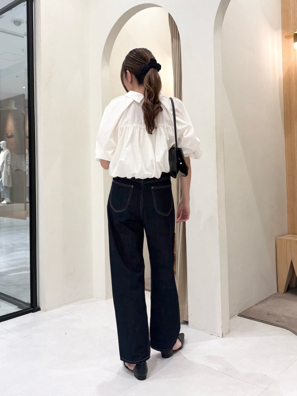 ブラック系のショルダーバッグ、ホワイト系のシャツ/ブラウス、ブラック系のデニムパンツを着用したレディースの春コーディネートの3枚目の写真