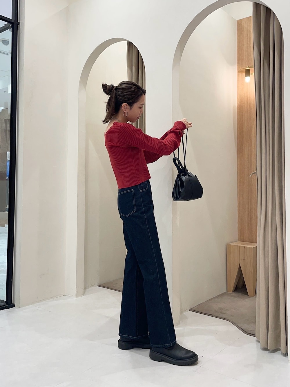 レッド系のカーディガン/ボレロ、ブラック系のショルダーバッグ、ブルー系のデニムパンツを着用したレディースの秋コーディネートの3枚目の写真