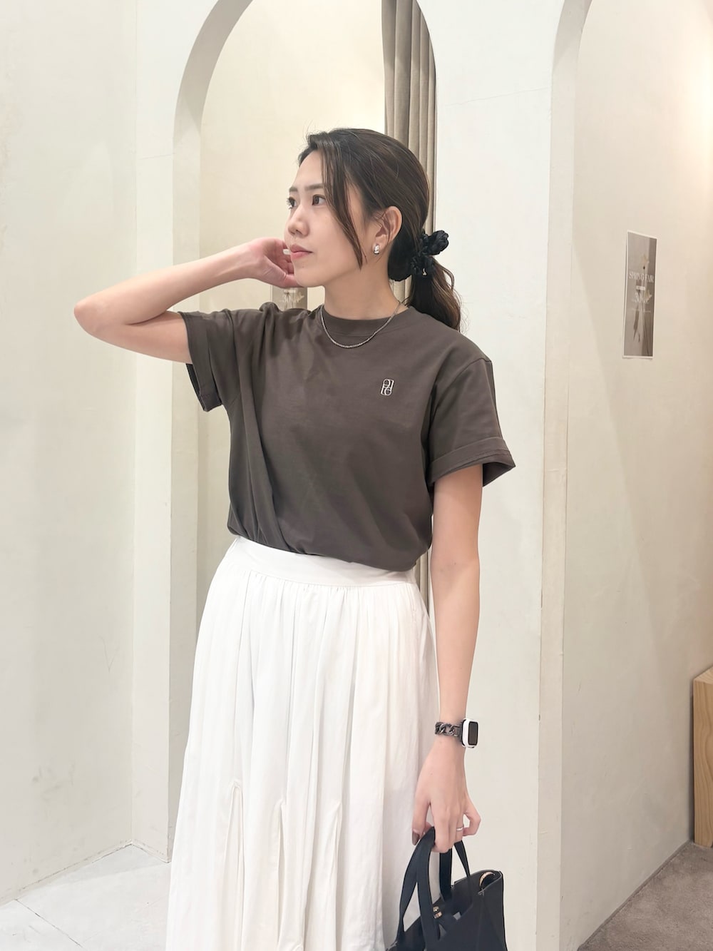 ブラック系のパンプス、ホワイト系のスカート、ブラック系のショルダーバッグを着用したレディースの春コーディネートの3枚目の写真