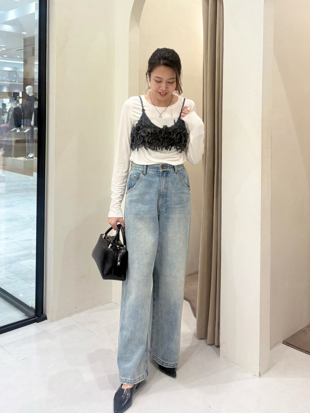 グレー系のTシャツ/カットソー、ブルー系のデニムパンツ、ブラック系のボストンバッグを着用したレディースの秋コーディネートの2枚目の写真