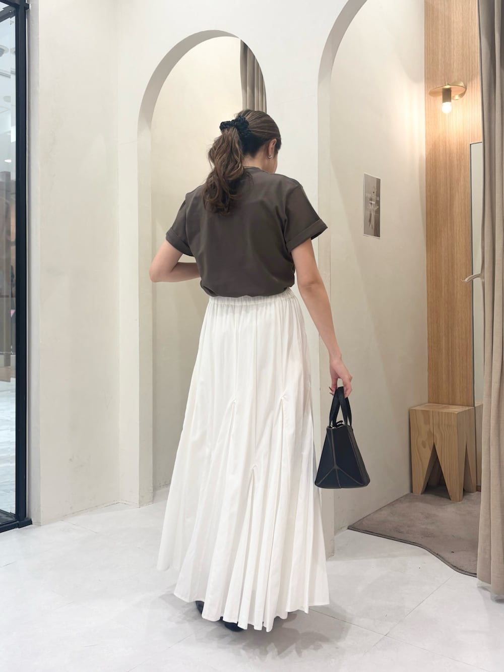 ブラック系のパンプス、ホワイト系のスカート、ブラック系のショルダーバッグを着用したレディースの春コーディネートの2枚目の写真