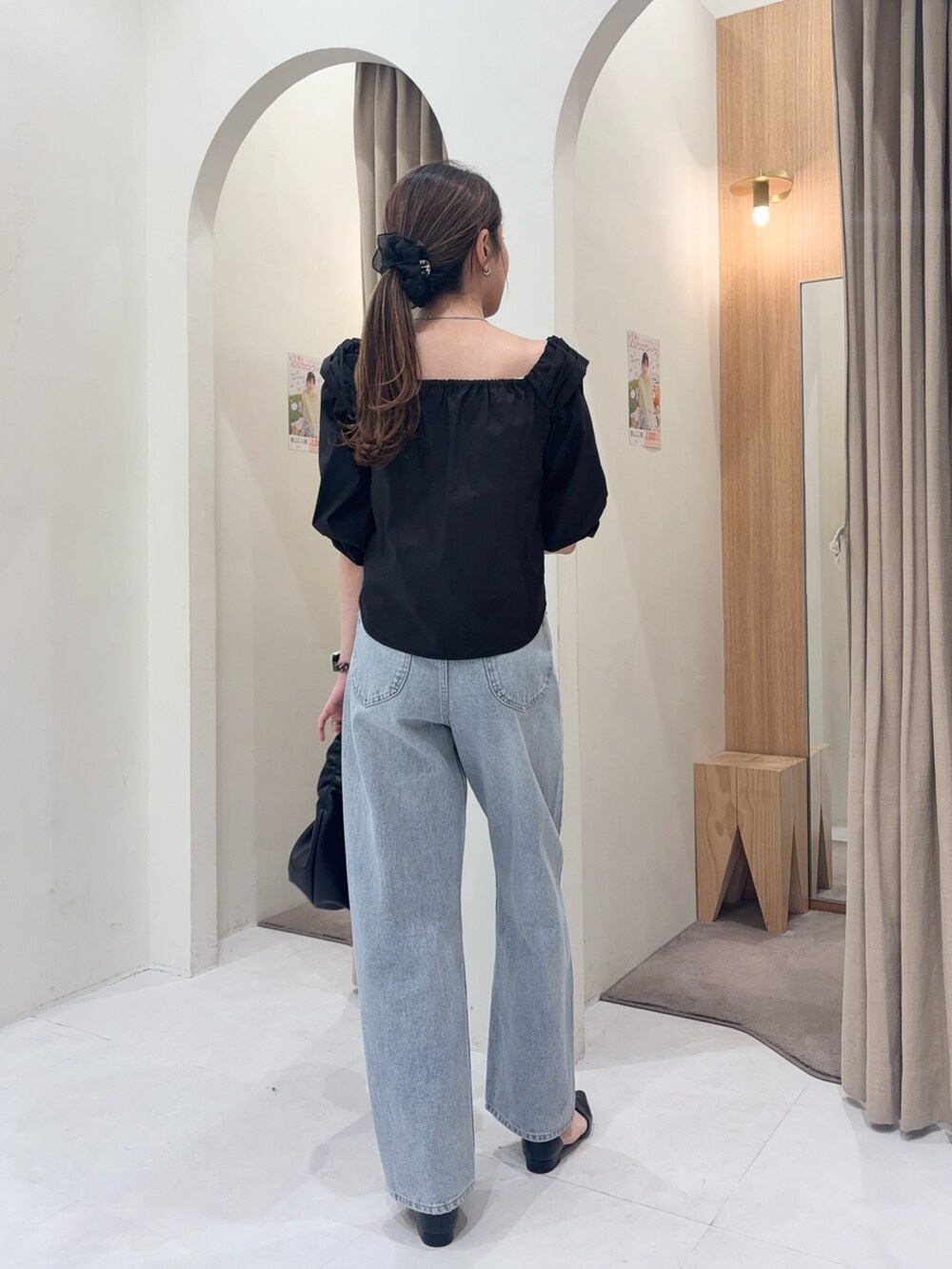 ブラック系のシャツ/ブラウス、ブラック系のショルダーバッグ、ブルー系のデニムパンツを着用したレディースの春コーディネートの2枚目の写真