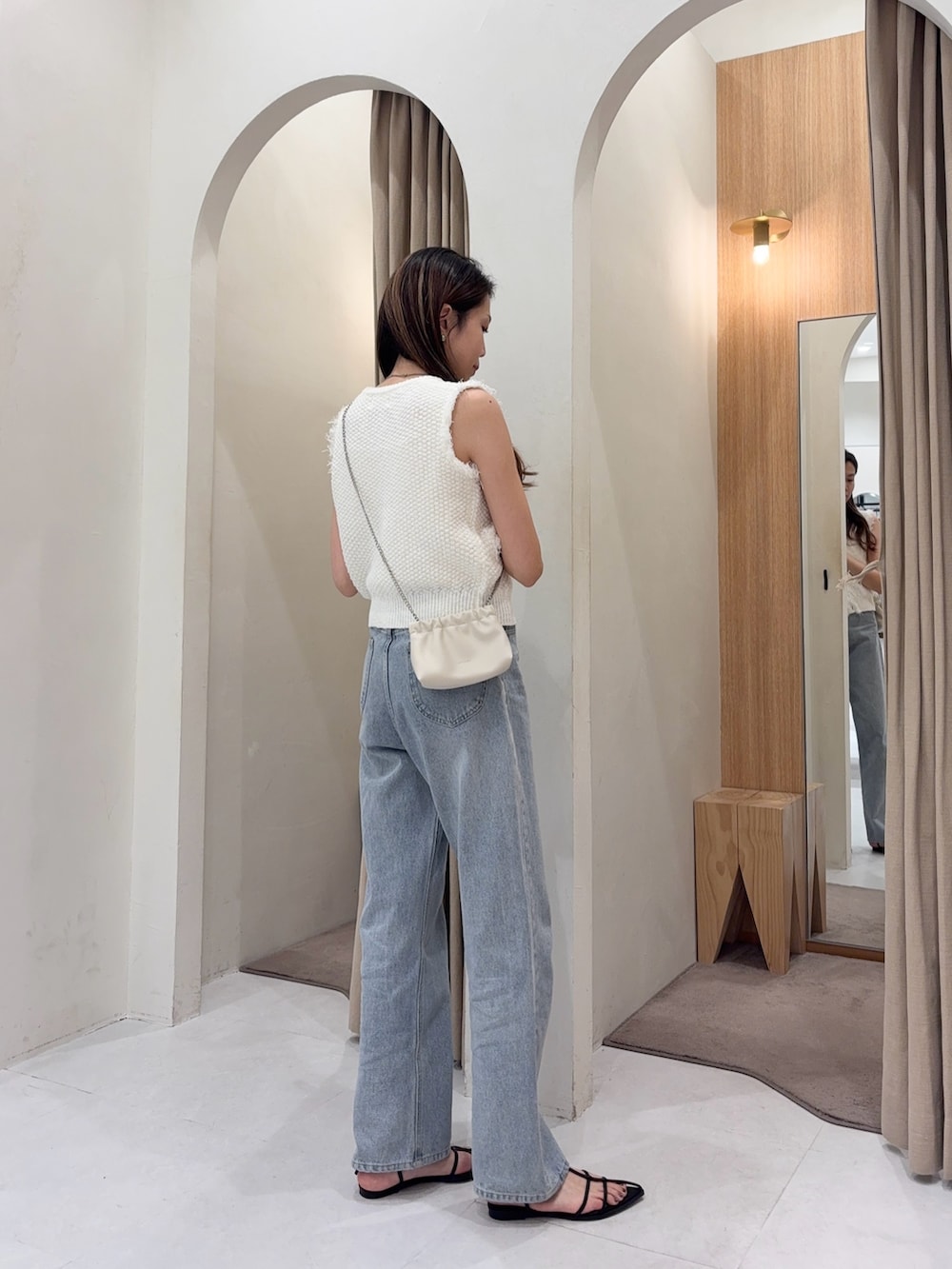 ホワイト系のニット/セーター、ホワイト系のショルダーバッグ、ブルー系のデニムパンツを着用したレディースの春コーディネートの4枚目の写真