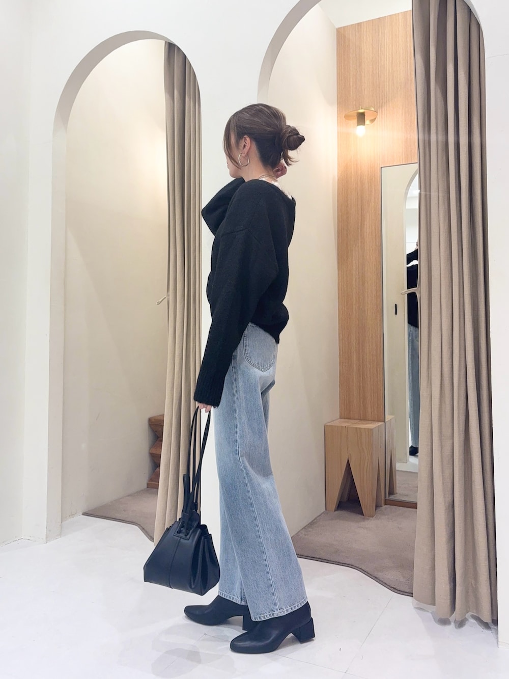 ブラック系のニット/セーター、ブルー系のデニムパンツ、ブラック系のショルダーバッグを着用したレディースの冬コーディネートの4枚目の写真