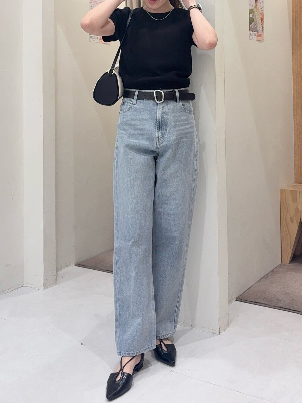 ブラック系のニット/セーター、ブラック系のショルダーバッグ、ブルー系のデニムパンツを着用したレディースの春コーディネートの2枚目の写真