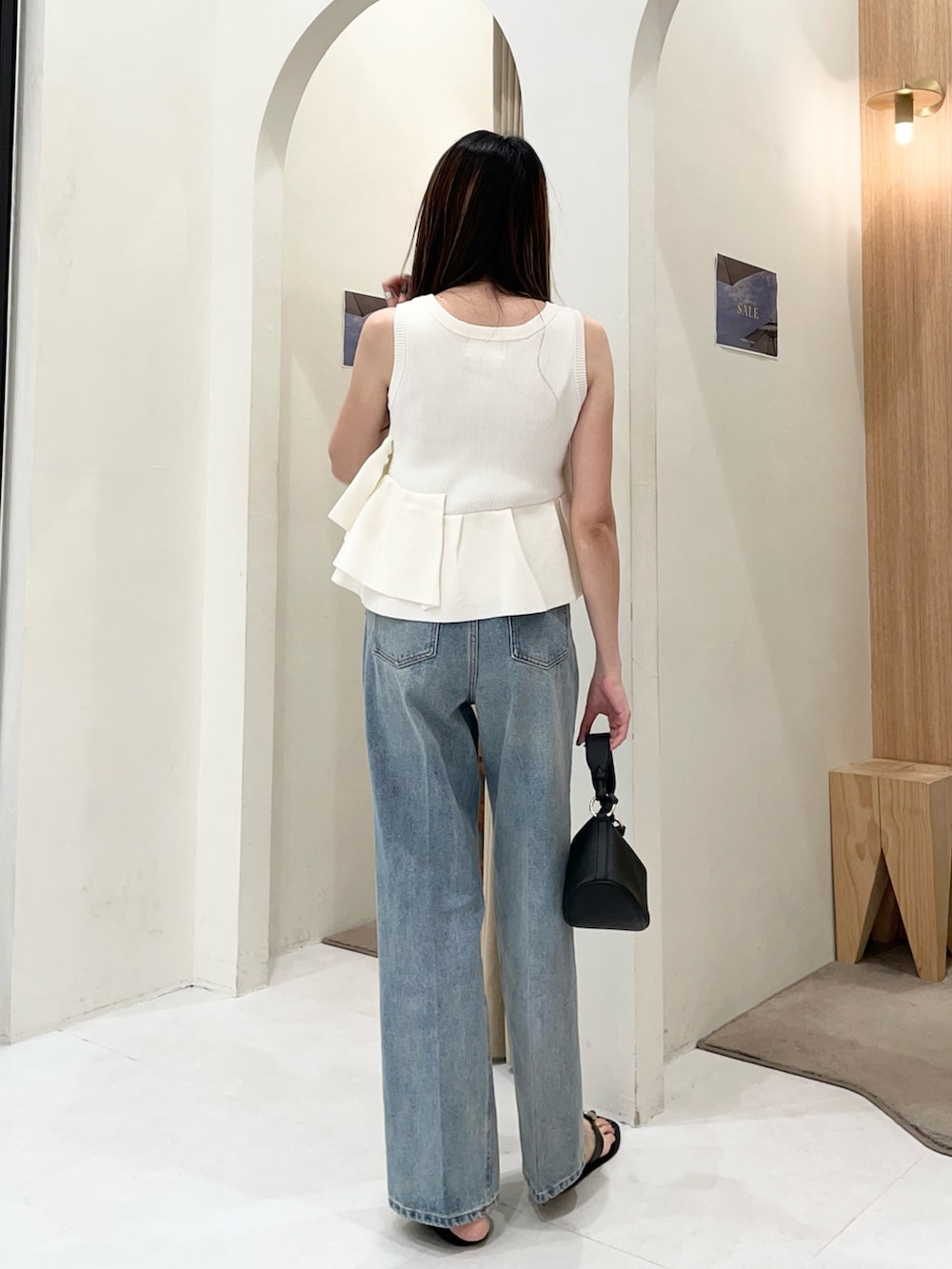 ホワイト系のニット/セーター、ブルー系のデニムパンツ、ブラック系のショルダーバッグを着用したレディースの夏コーディネートの3枚目の写真