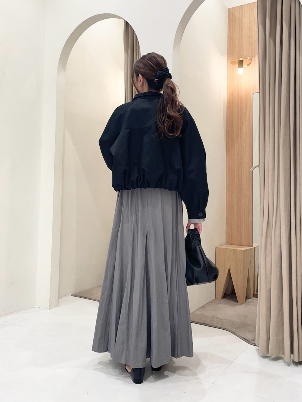 ブラック系のトレンチコート、グレー系のTシャツ/カットソー、グレー系のスカートを着用したレディースの春コーディネートの2枚目の写真