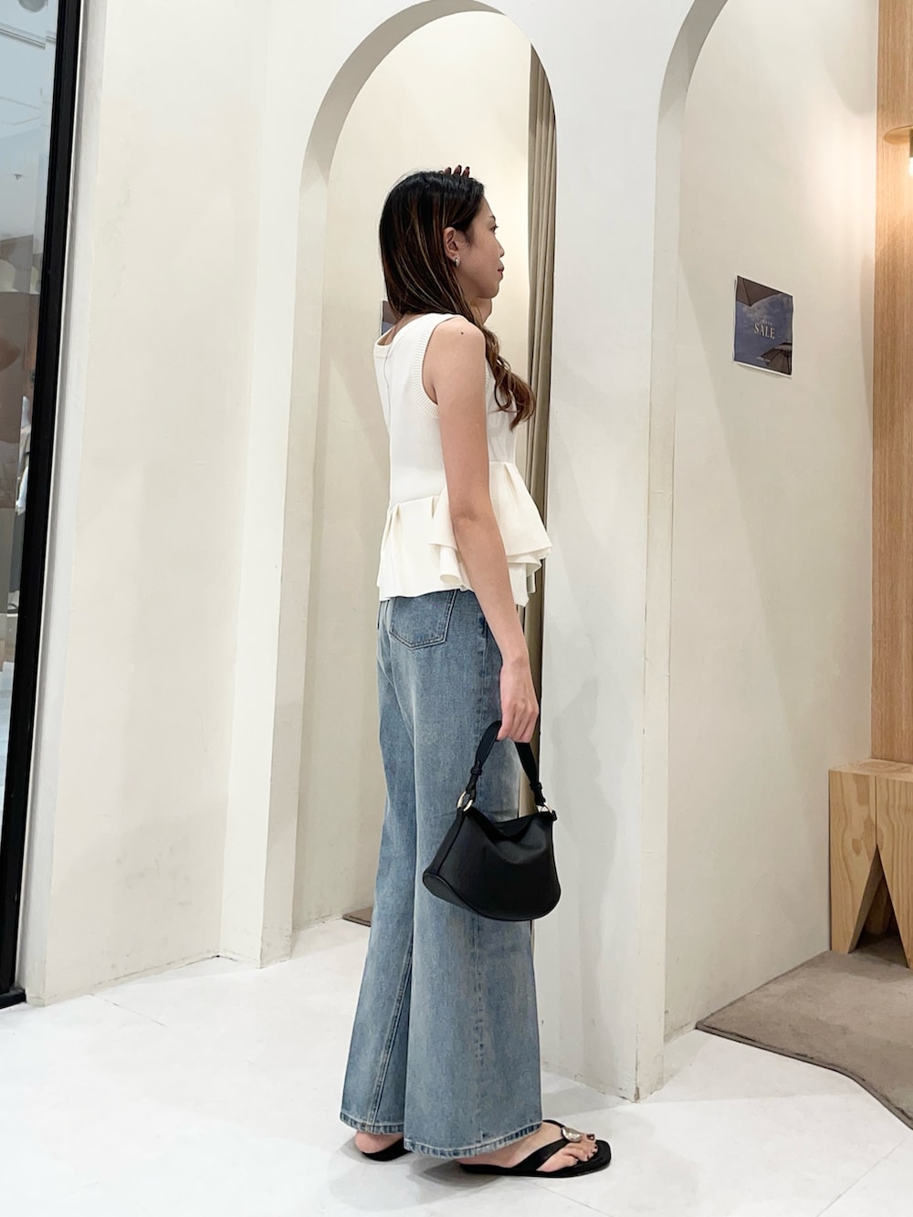 ホワイト系のニット/セーター、ブルー系のデニムパンツ、ブラック系のショルダーバッグを着用したレディースの夏コーディネートの2枚目の写真