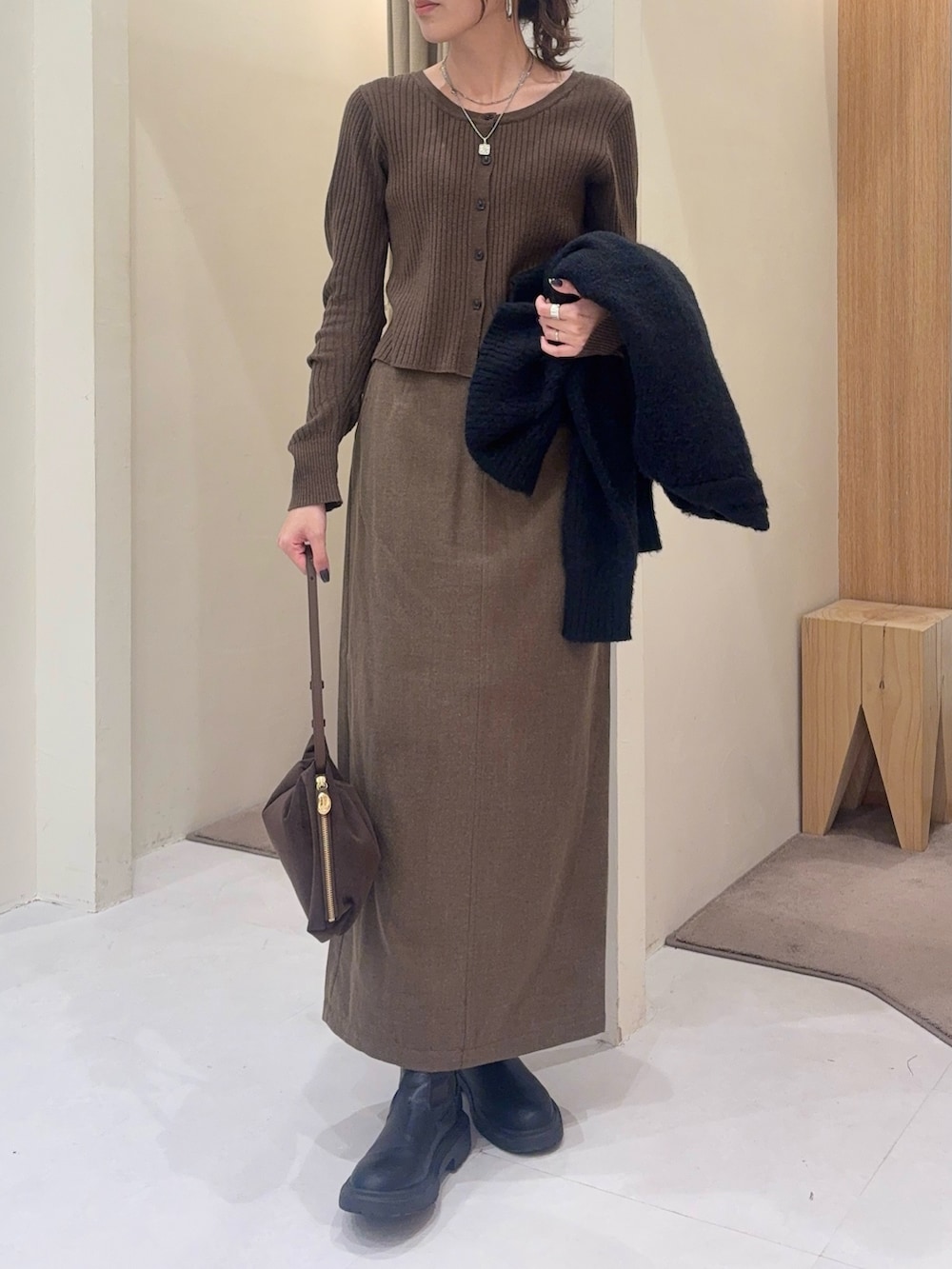 ブラウン系のカーディガン/ボレロ、ブラウン系のスカート、ブラック系のカーディガン/ボレロを着用したレディースの秋コーディネートの2枚目の写真