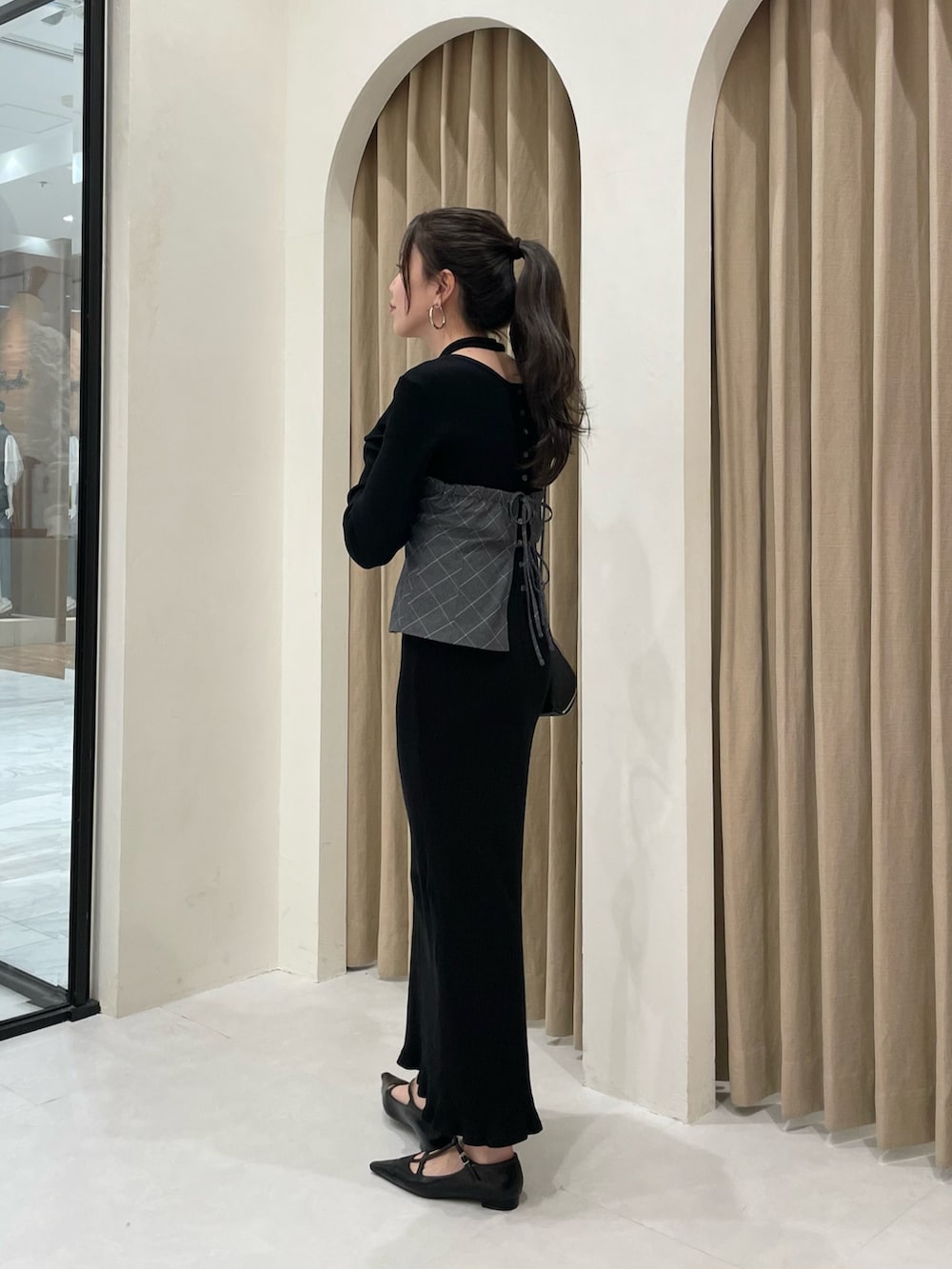 ブラック系のワンピース、ブラック系のパンプス、グレー系のシャツ/ブラウスを着用したレディースの春コーディネートの2枚目の写真