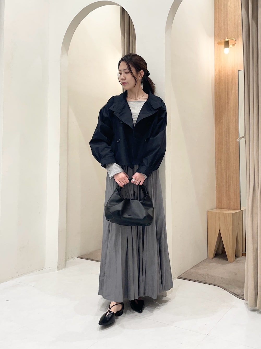 ブラック系のトレンチコート、グレー系のTシャツ/カットソー、グレー系のスカートを着用したレディースの春コーディネートの4枚目の写真