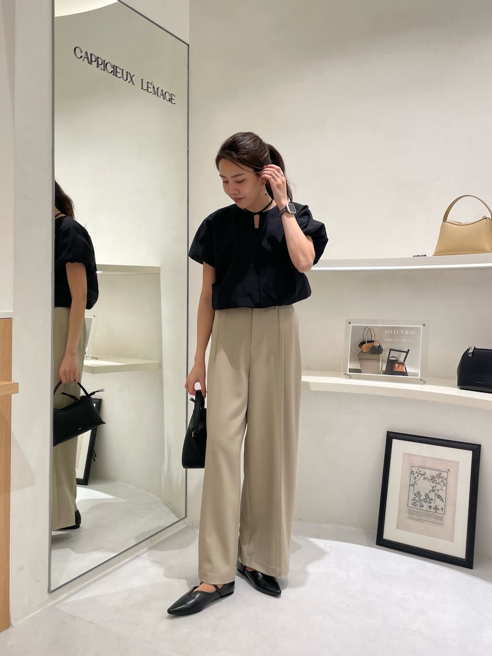 ブラック系のシャツ/ブラウス、ブラック系のショルダーバッグ、ベージュ系のその他パンツを着用したレディースの春コーディネートの2枚目の写真