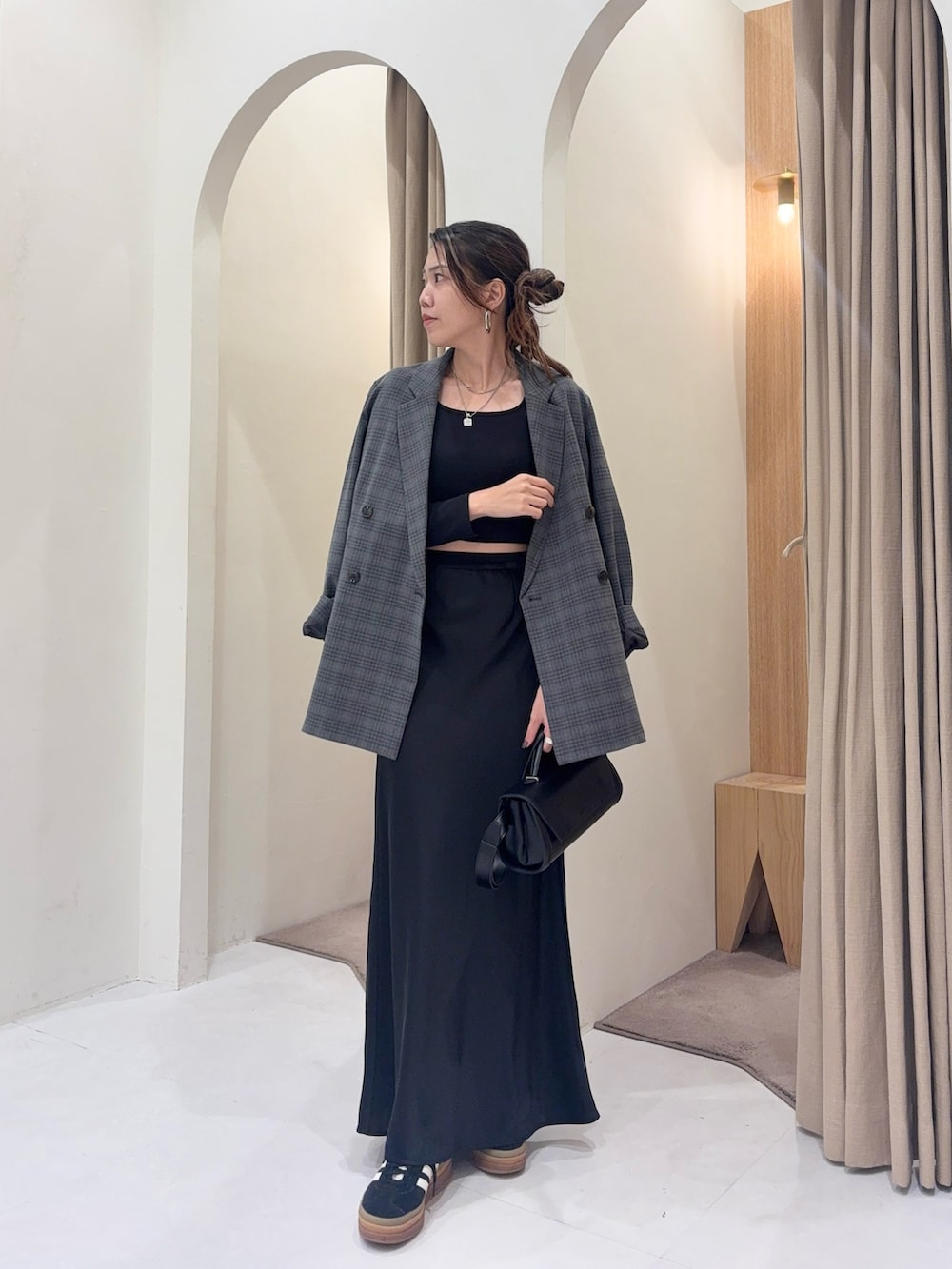 グレー系のテーラードジャケット、ブラック系のスカート、ブラック系のショルダーバッグを着用したレディースの秋コーディネートの3枚目の写真