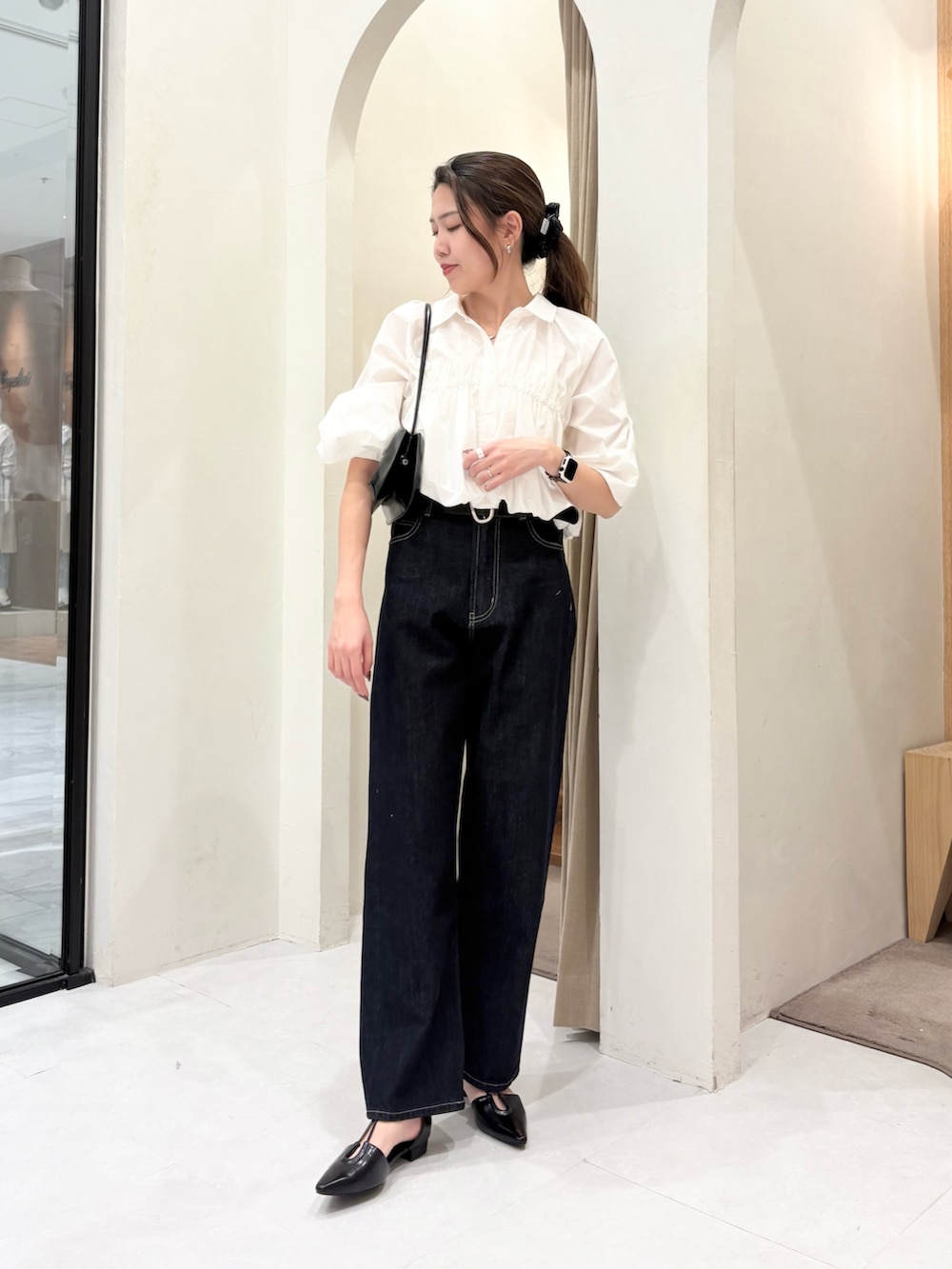 ブラック系のショルダーバッグ、ホワイト系のシャツ/ブラウス、ブラック系のデニムパンツを着用したレディースの春コーディネートの2枚目の写真