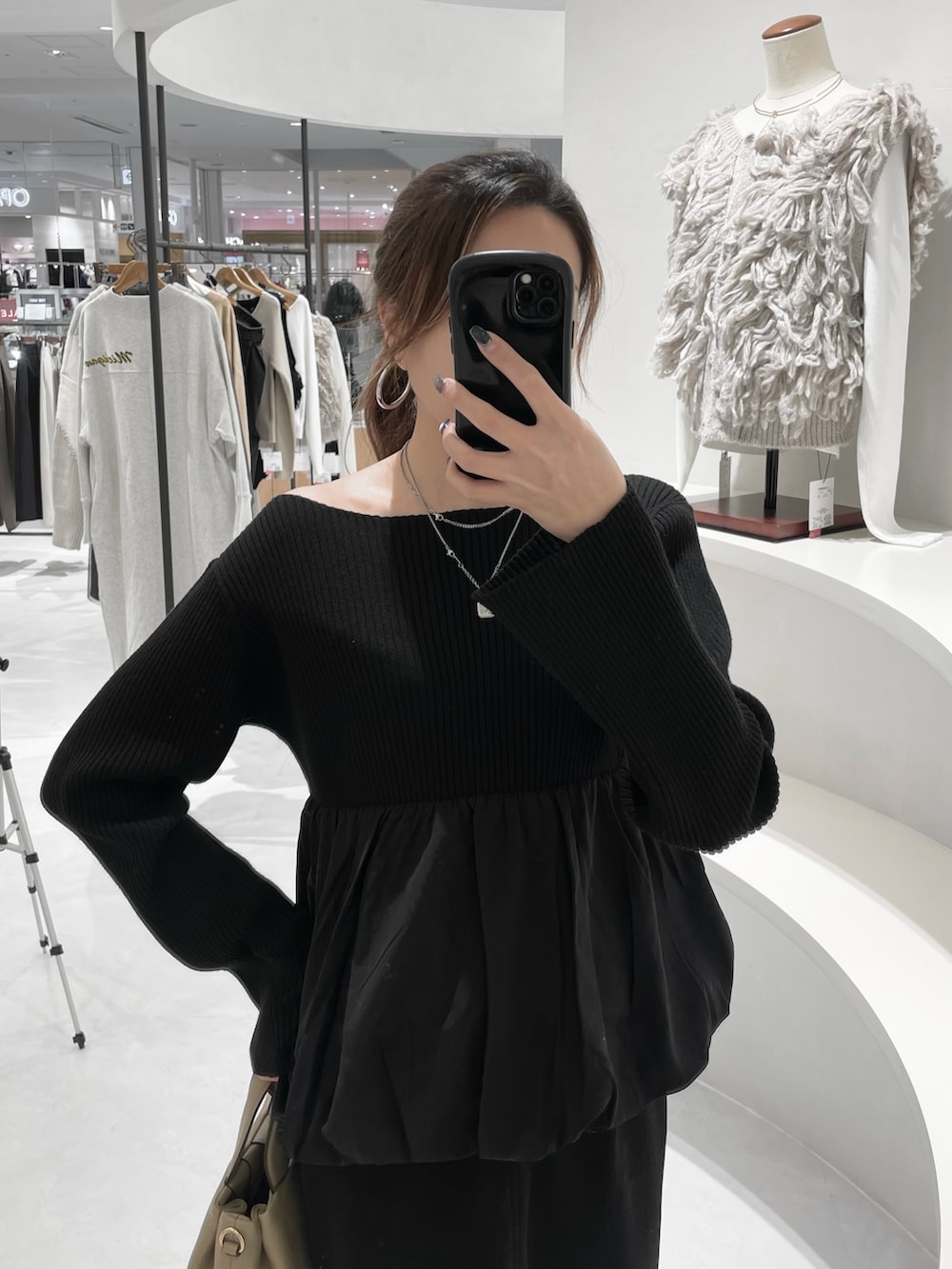 ブラック系のニット/セーター、ブラック系のスカート、ベージュ系のショルダーバッグを着用したレディースの冬コーディネートの2枚目の写真