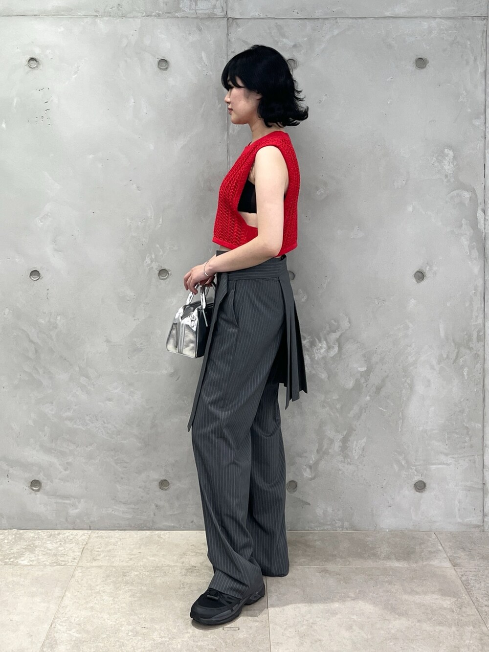 レッド系のベスト、グレー系のその他パンツ、シルバー系のボストンバッグを着用したレディースの夏コーディネートの2枚目の写真