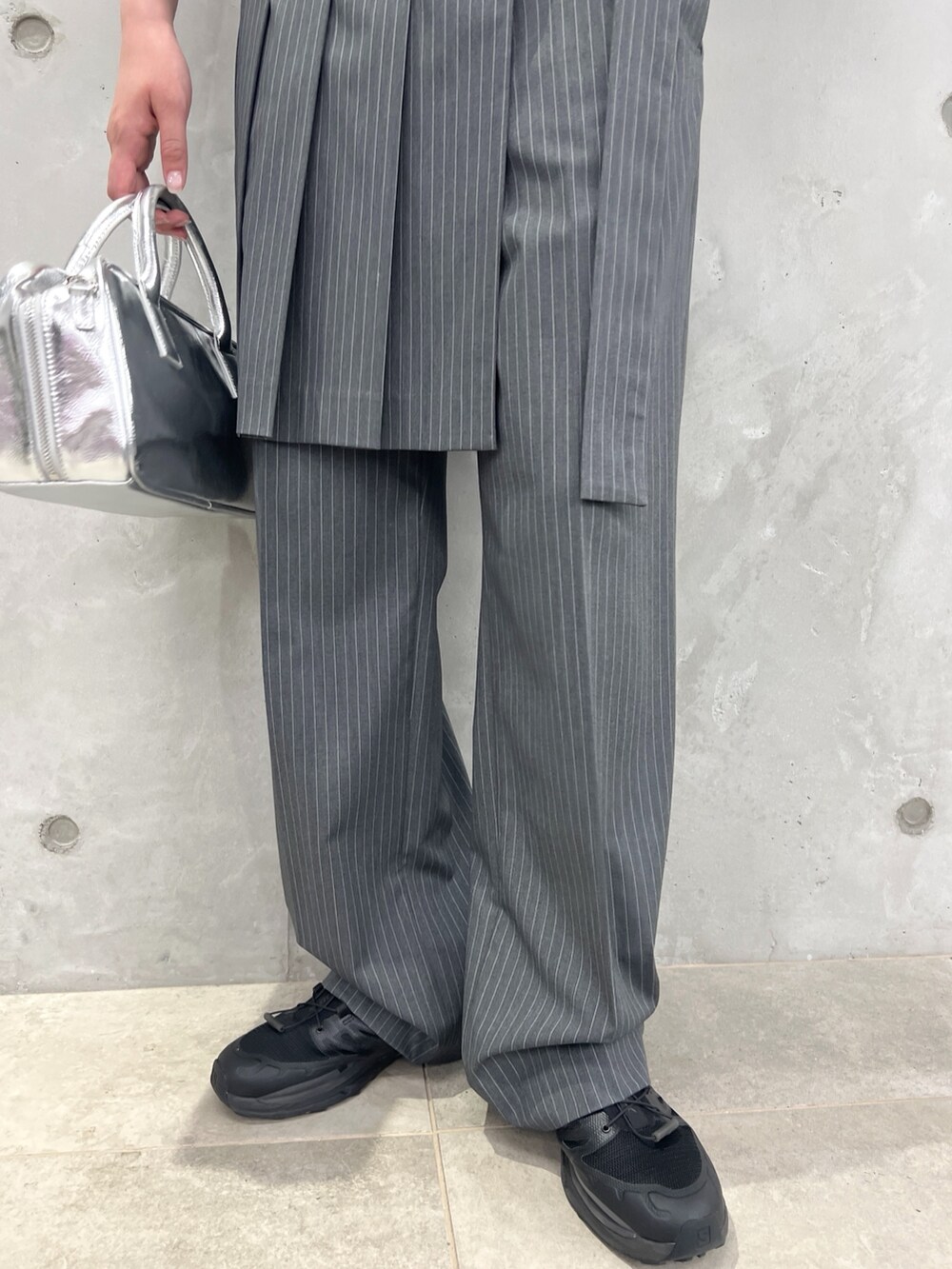 レッド系のベスト、グレー系のその他パンツ、シルバー系のボストンバッグを着用したレディースの夏コーディネートの6枚目の写真