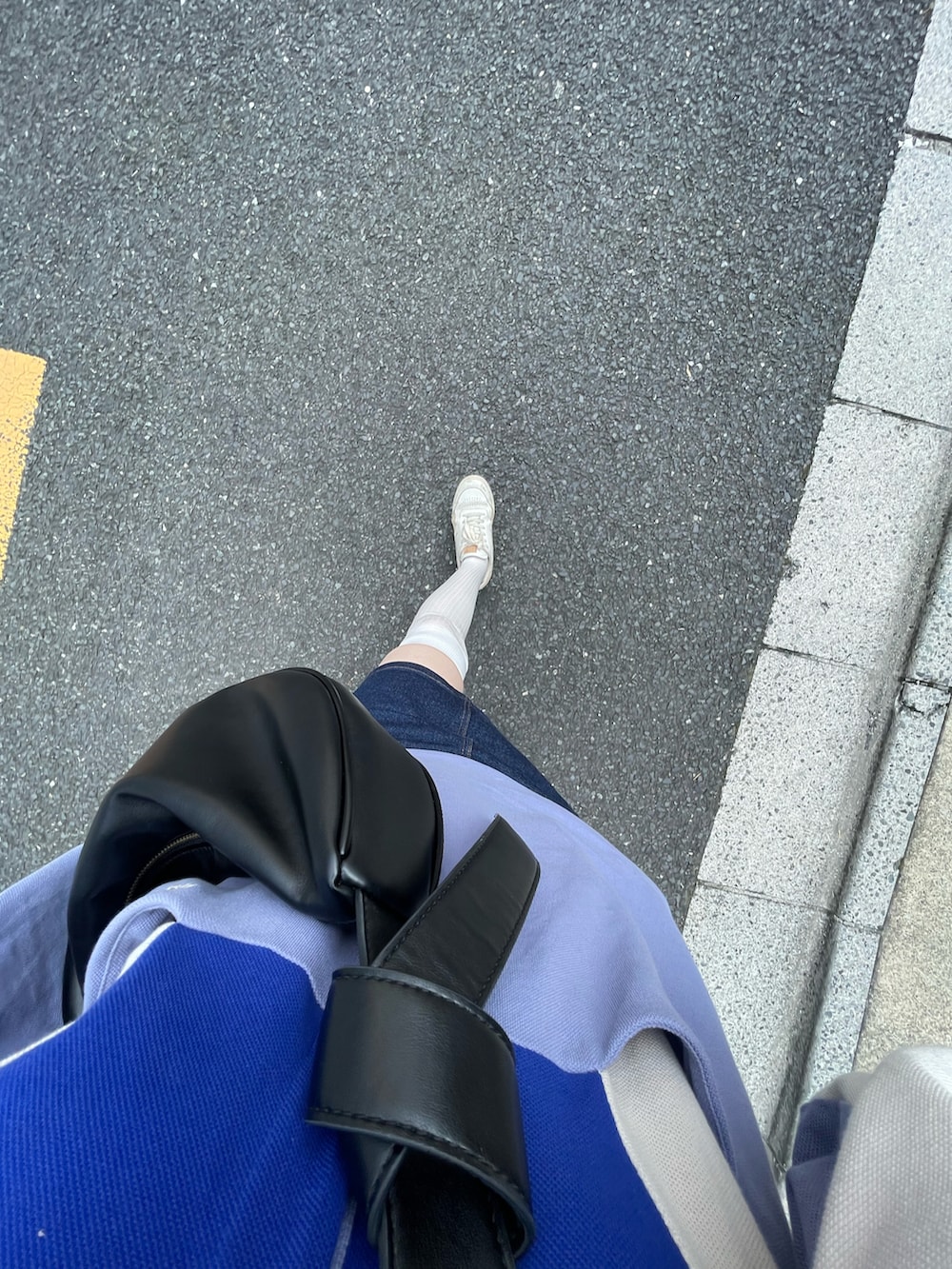 ブラック系のショルダーバッグ、ブルー系のデニムスカート、ホワイト系のスニーカーを着用したレディースの夏コーディネートの2枚目の写真