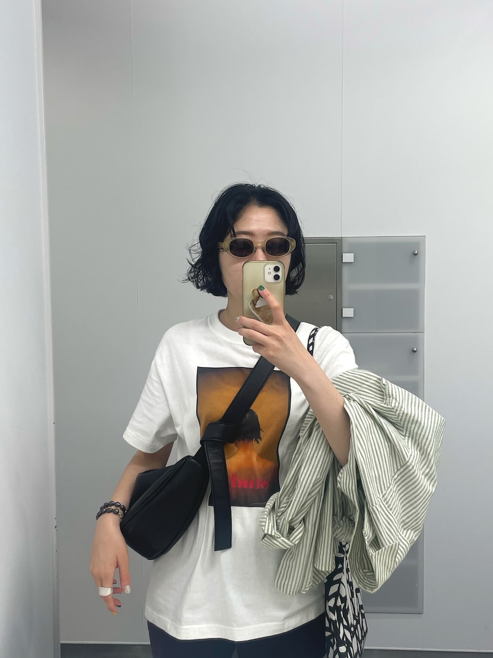 ブラック系のショルダーバッグ、ホワイト系のTシャツ/カットソーを着用したレディースの夏コーディネートの2枚目の写真