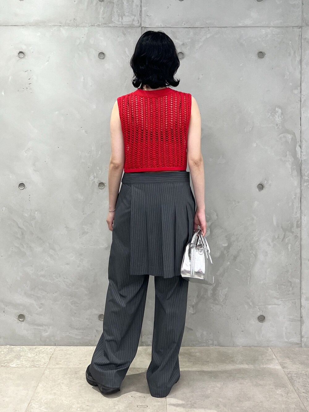 レッド系のベスト、グレー系のその他パンツ、シルバー系のボストンバッグを着用したレディースの夏コーディネートの3枚目の写真