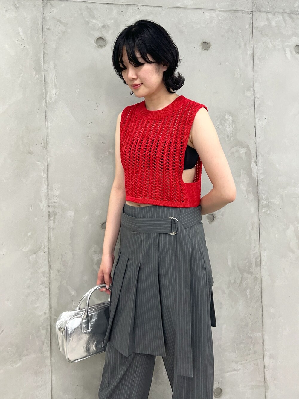 レッド系のベスト、グレー系のその他パンツ、シルバー系のボストンバッグを着用したレディースの夏コーディネートの5枚目の写真