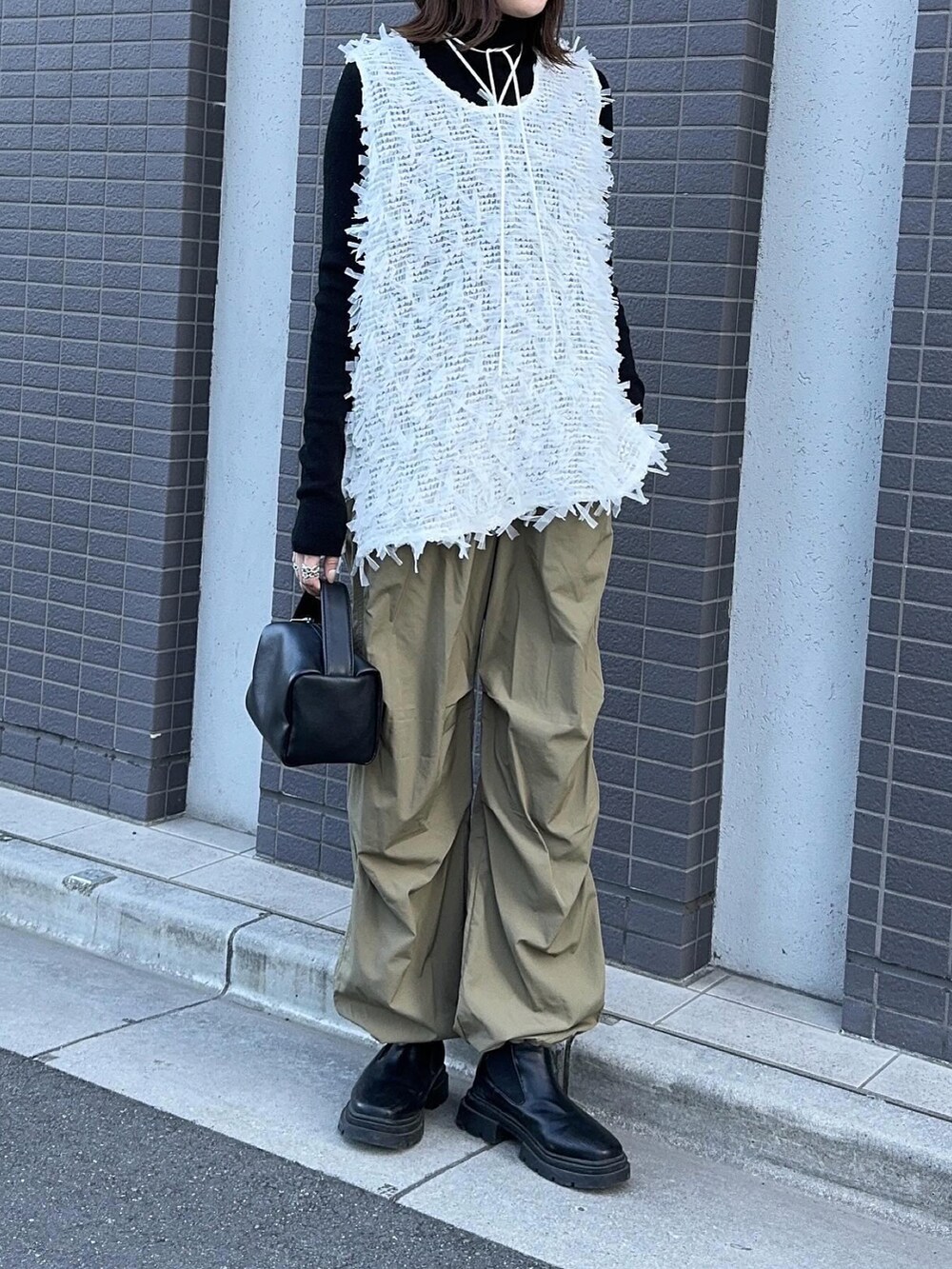 ホワイト系のトップス、グリーン系のパンツ、ブラック系のハンドバッグを着用したレディースの冬コーディネートの3枚目の写真