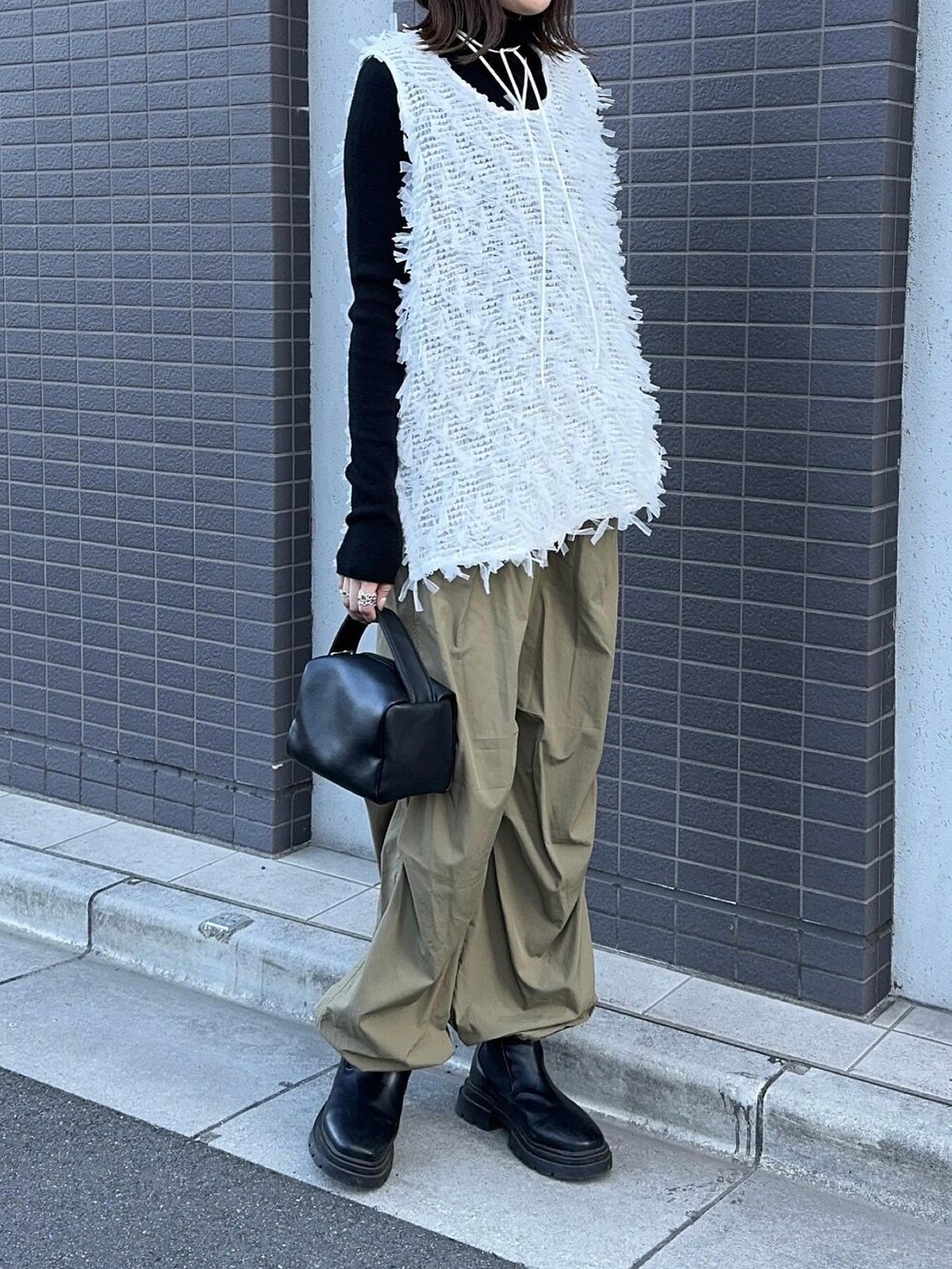 ホワイト系のトップス、グリーン系のパンツ、ブラック系のハンドバッグを着用したレディースの冬コーディネートの4枚目の写真