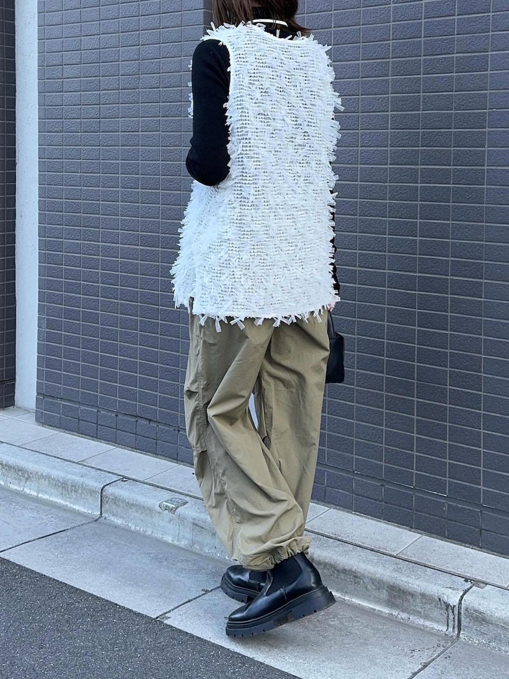 ホワイト系のトップス、グリーン系のパンツ、ブラック系のハンドバッグを着用したレディースの冬コーディネートの5枚目の写真