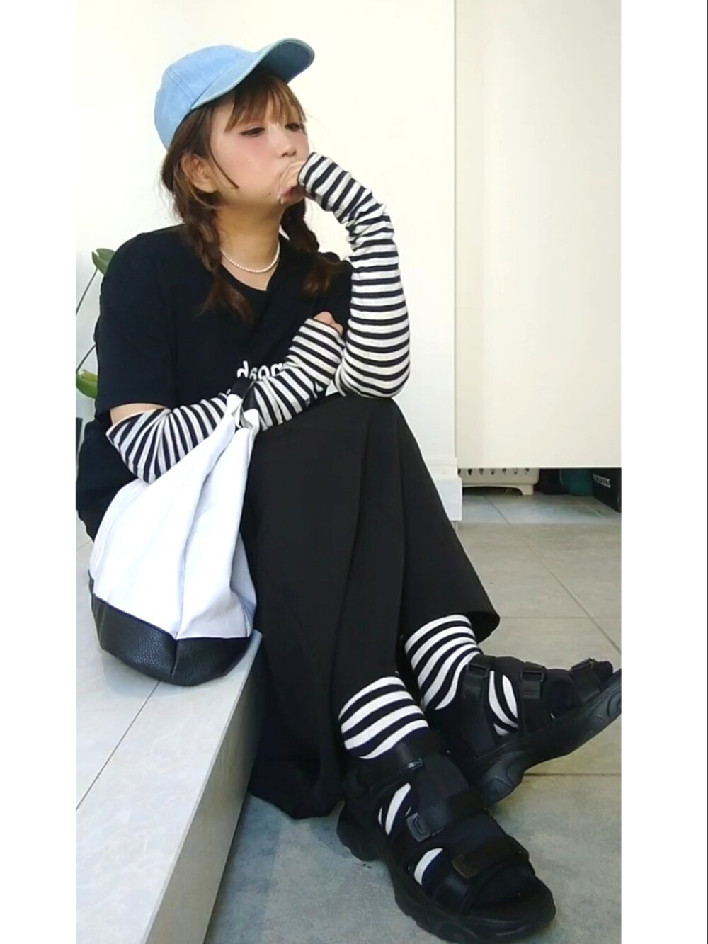 ブラック系のスカート、ブルー系のキャップ、グレー系のアームカバーを着用したレディースの夏コーディネートの2枚目の写真