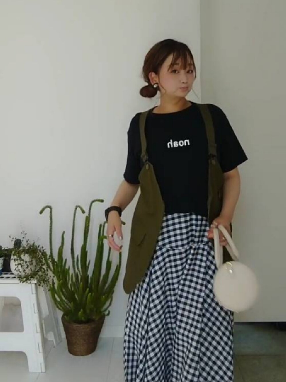 グリーン系のベスト、ブルー系のTシャツ/カットソー、ホワイト系のショルダーバッグを着用したレディースの夏コーディネートの2枚目の写真