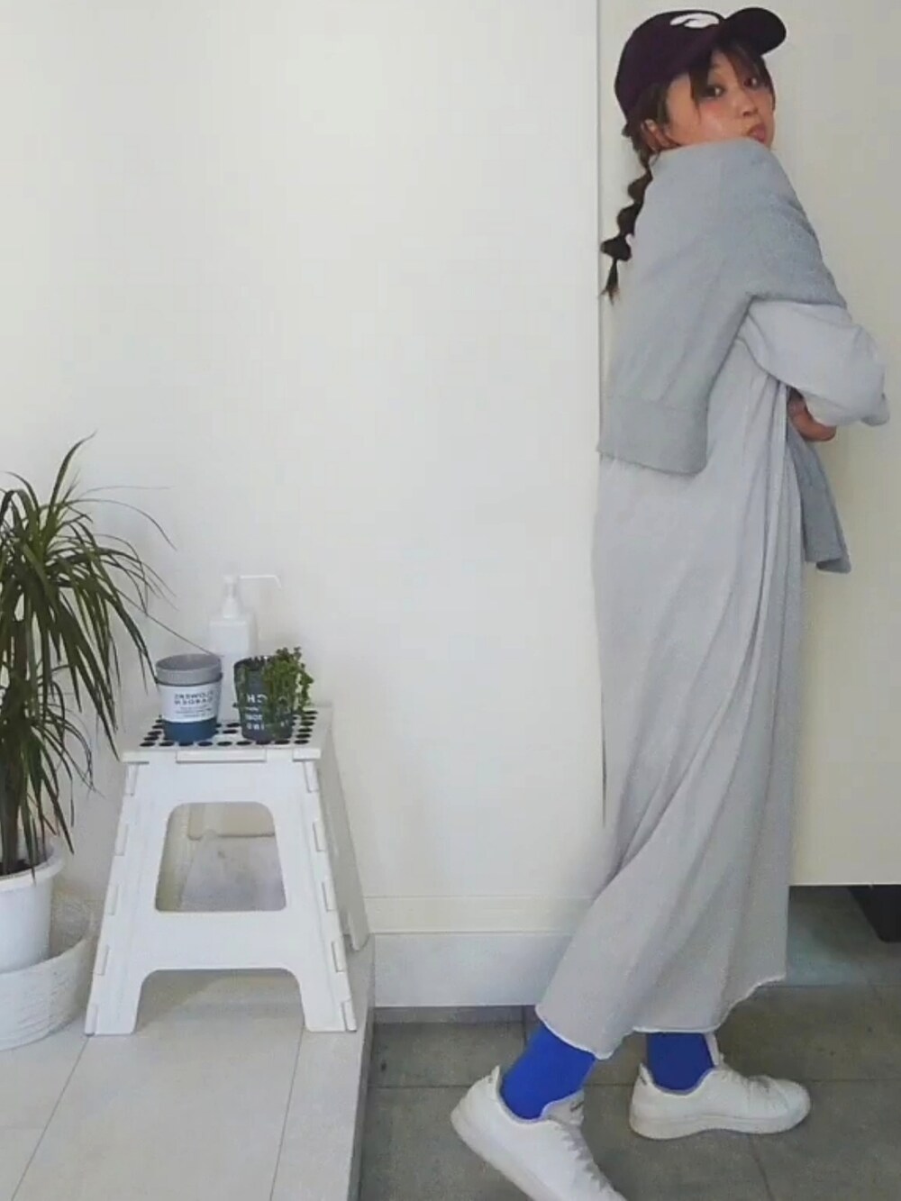 グレー系のワンピース、レッド系のキャップを着用したレディースの春コーディネートの2枚目の写真