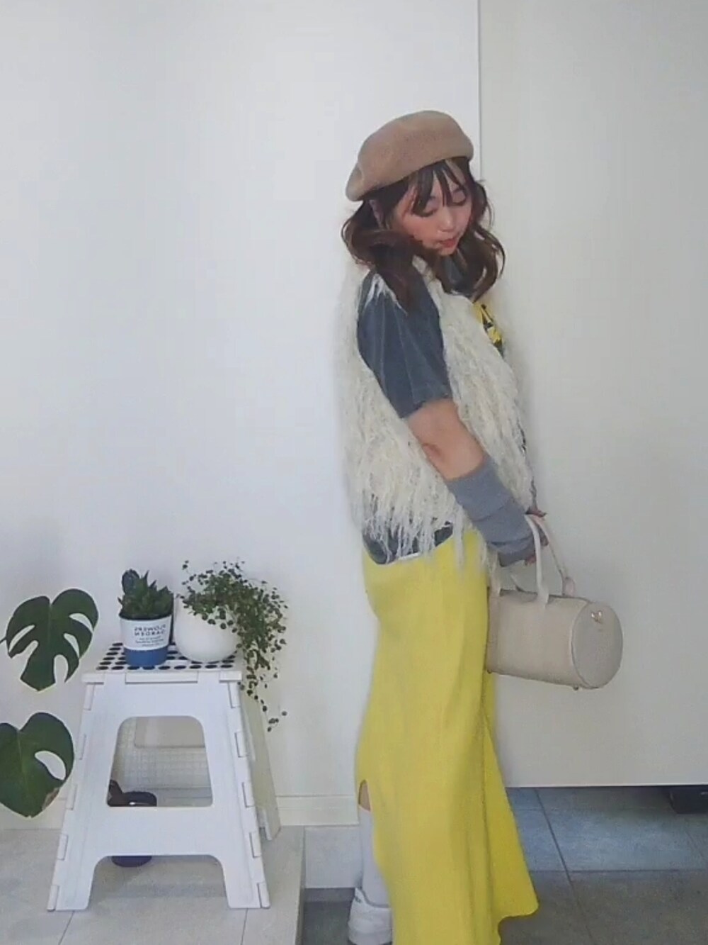 ブラック系のTシャツ/カットソー、イエロー系のスカート、グレー系のニット/セーターを着用したレディースの春コーディネートの2枚目の写真