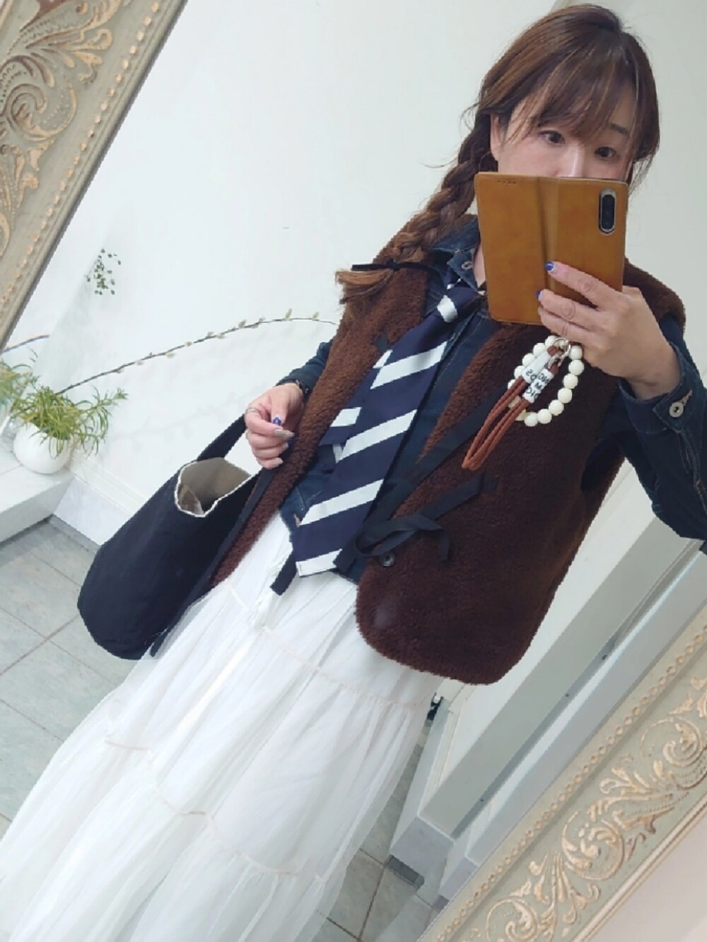 ブラウン系のベスト、ホワイト系のスカート、ホワイト系のスカートを着用したレディースの春コーディネートの2枚目の写真
