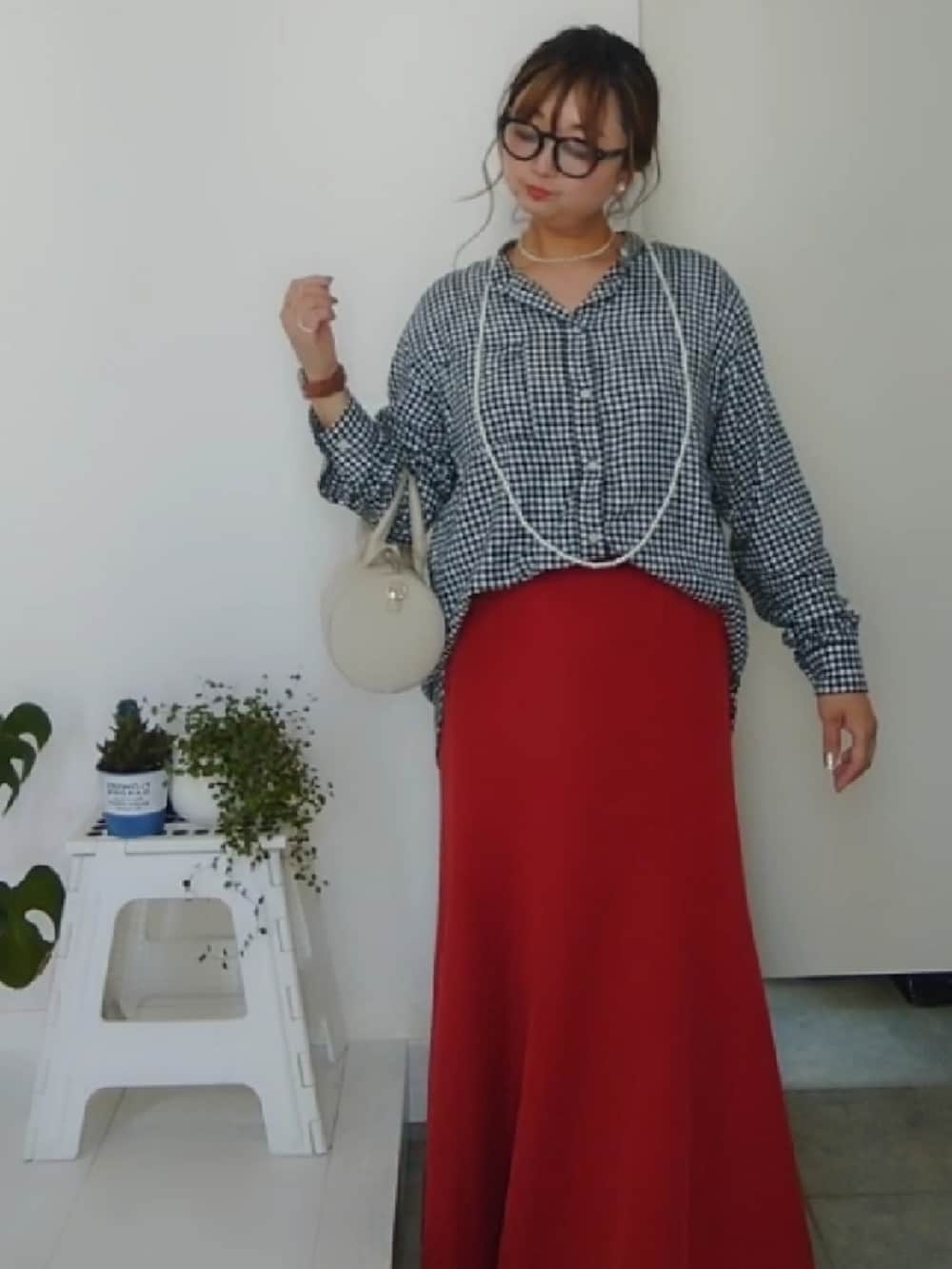 ブラック系のシャツ/ブラウス、オレンジ系のスカート、ホワイト系のショルダーバッグを着用したレディースの春コーディネートの2枚目の写真