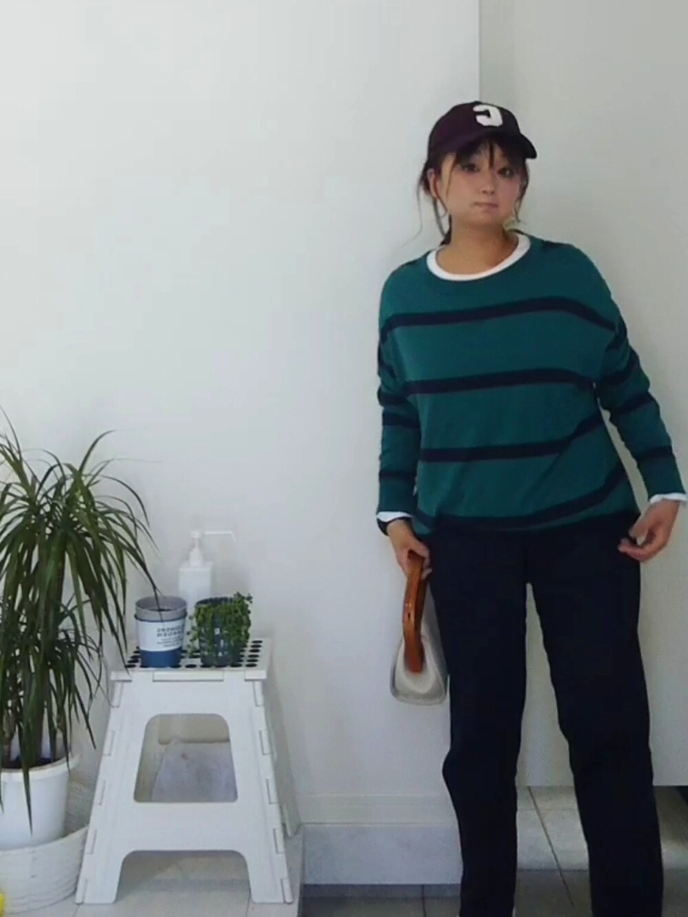 グリーン系のTシャツ/カットソー、ホワイト系のクラッチバッグ、ホワイト系のスニーカーを着用したレディースの春コーディネートの4枚目の写真