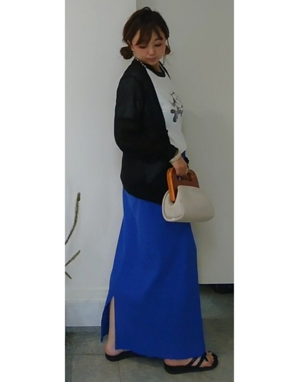 ホワイト系のクラッチバッグ、ブルー系のスカート、ブラック系のサンダルを着用したレディースの夏コーディネートの2枚目の写真