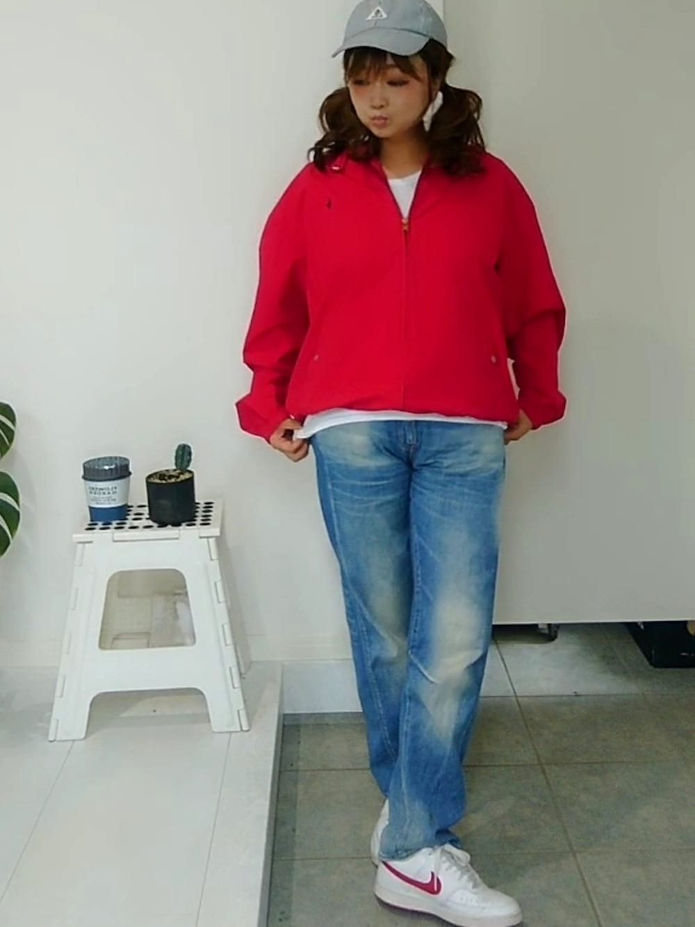 レッド系のブルゾン、ブルー系のデニムパンツ、ホワイト系のスニーカーを着用したレディースの秋コーディネートの4枚目の写真