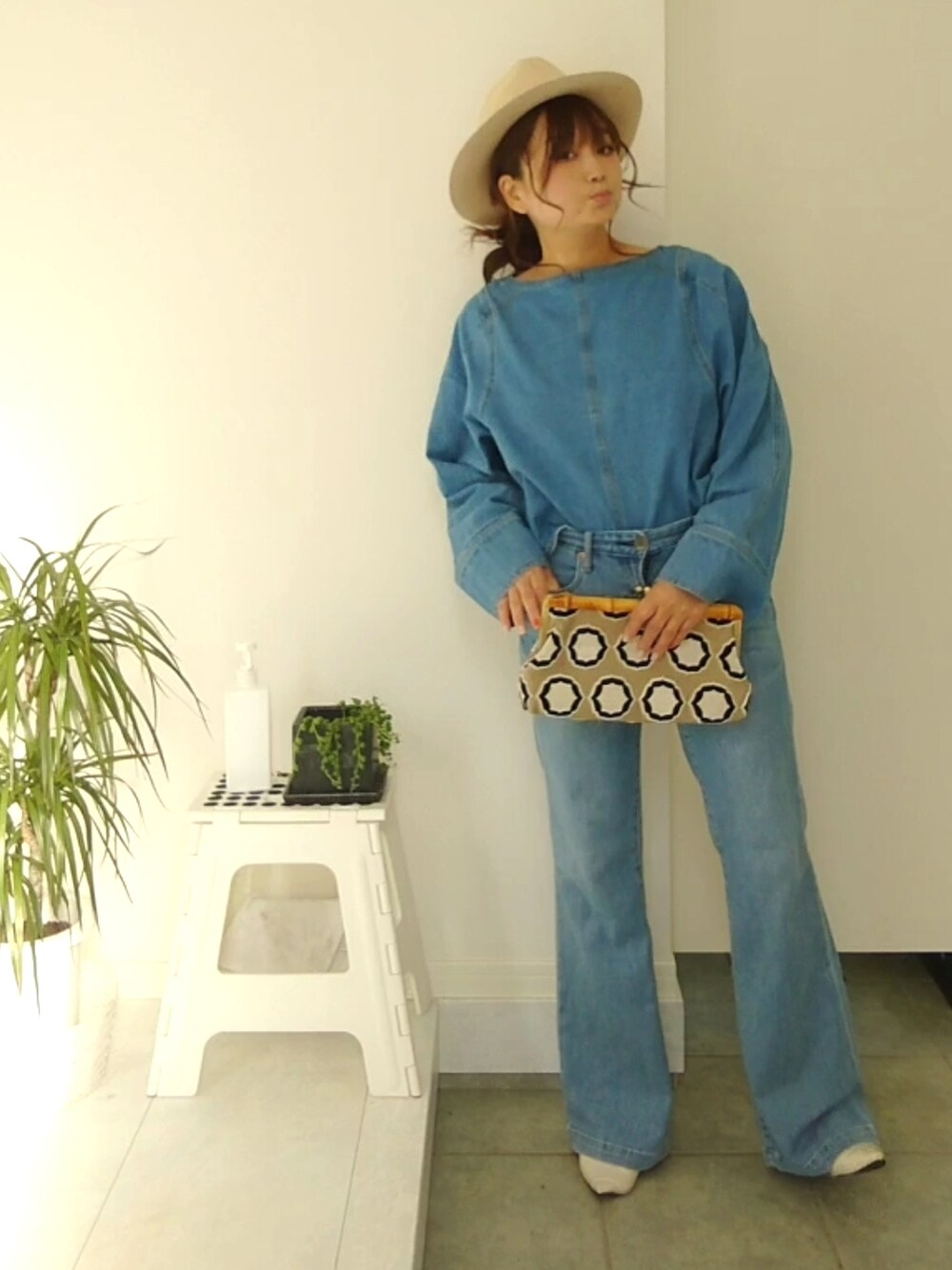 ブルー系のデニムパンツ、ブルー系のシャツ/ブラウス、ベージュ系のクラッチバッグを着用したレディースの春コーディネートの2枚目の写真
