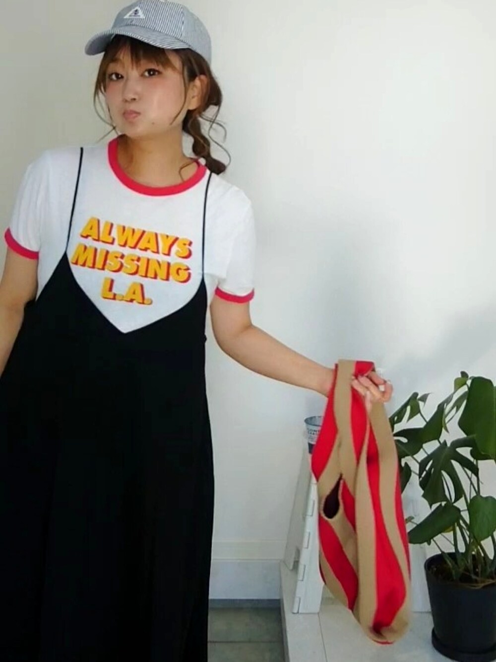 ブラック系のワンピース、レッド系のスニーカー、ブラック系のキャップを着用したレディースの秋コーディネートの3枚目の写真