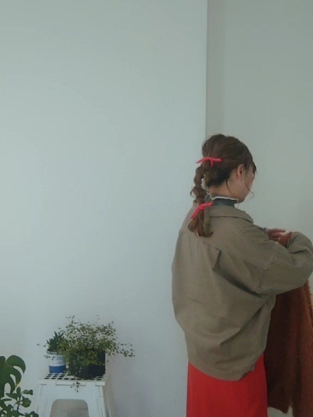 オレンジ系のスカート、ベージュ系のその他アウター、ホワイト系のニット/セーターを着用したレディースの冬コーディネートの2枚目の写真