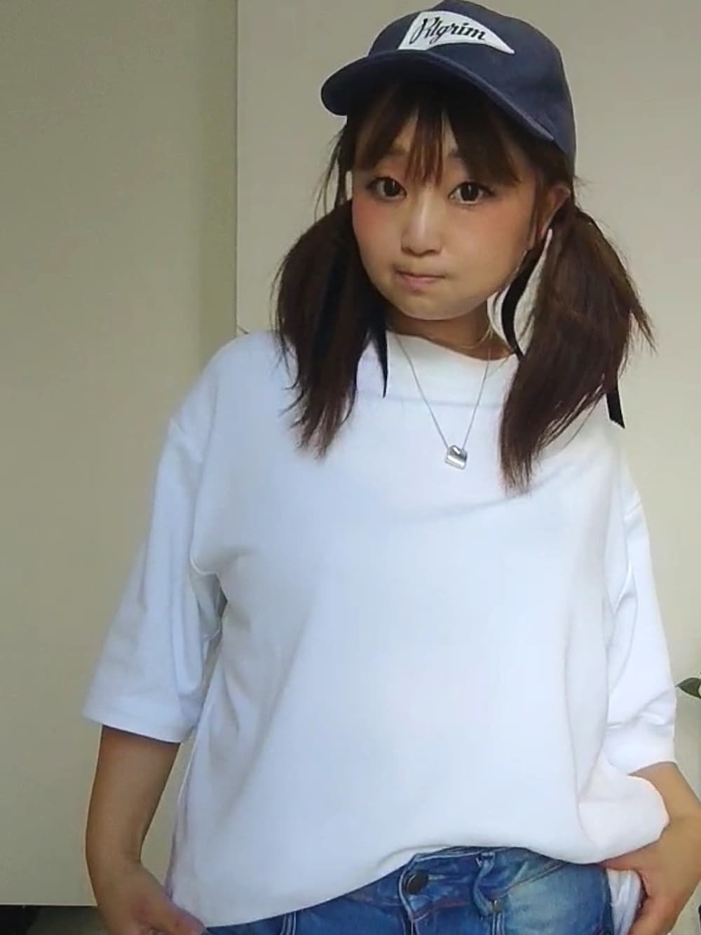 ブルー系のデニムパンツ、ブラック系のスニーカー、ブルー系のキャップを着用したレディースの夏コーディネートの2枚目の写真