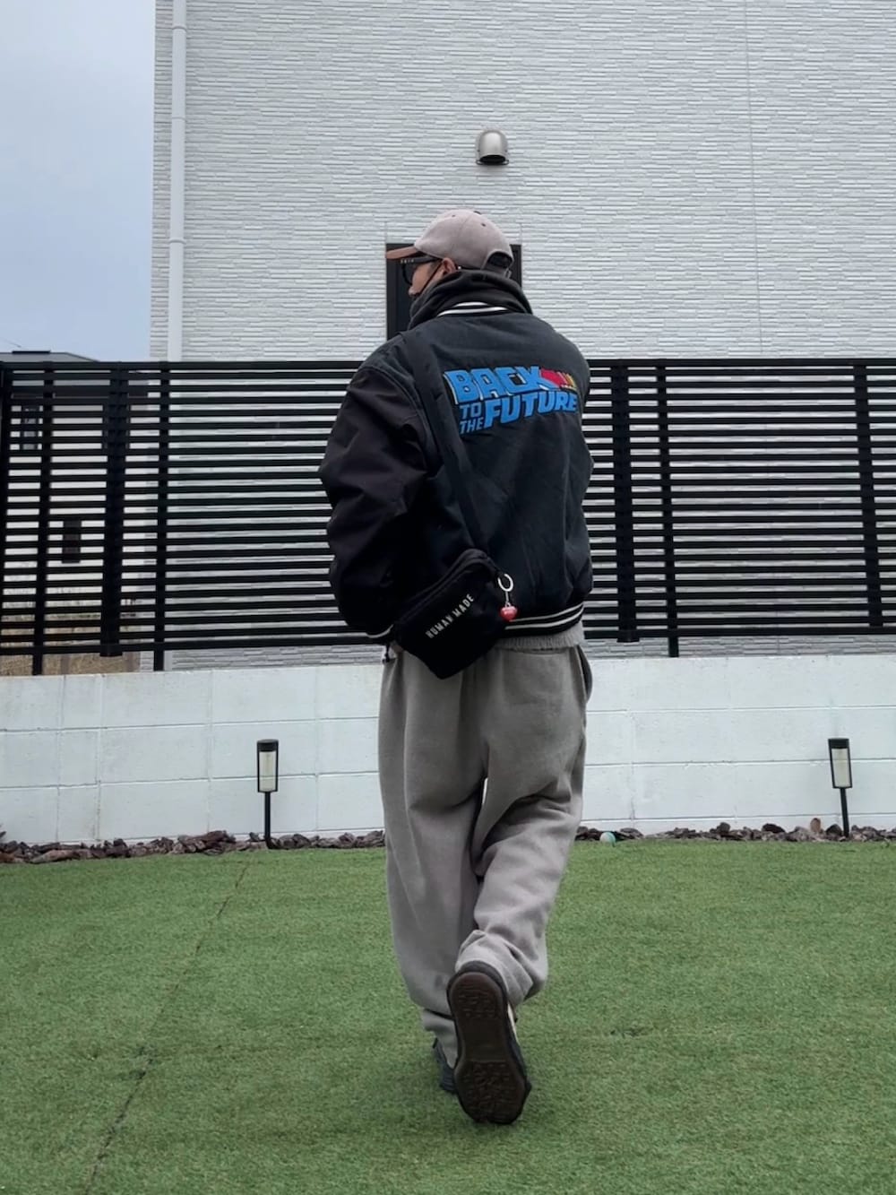 グレー系のニット/セーター、ベージュ系のスラックス、ブラック系のスタジャンを着用したメンズの冬コーディネートの3枚目の写真