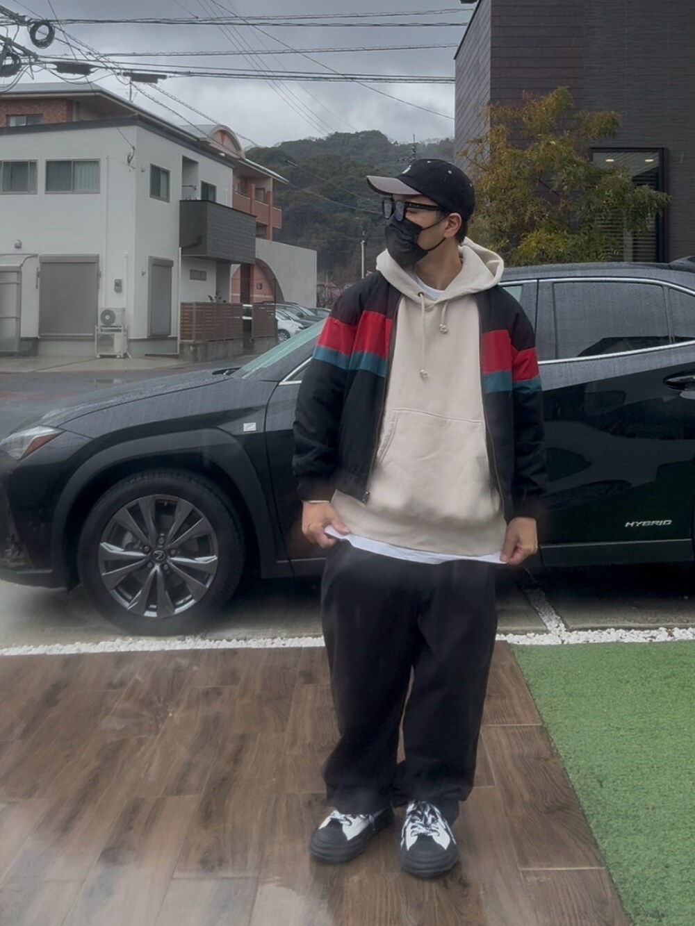 ブラック系のブルゾン、ベージュ系のパーカー、ブラック系のチノパンツを着用したメンズの春コーディネートの2枚目の写真