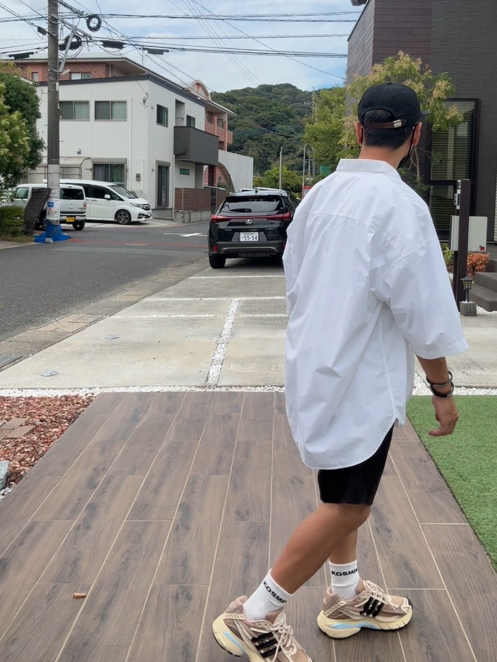 ホワイト系のTシャツ/カットソー、ベージュ系のスニーカー、ブラック系のキャップを着用したメンズの秋コーディネートの2枚目の写真