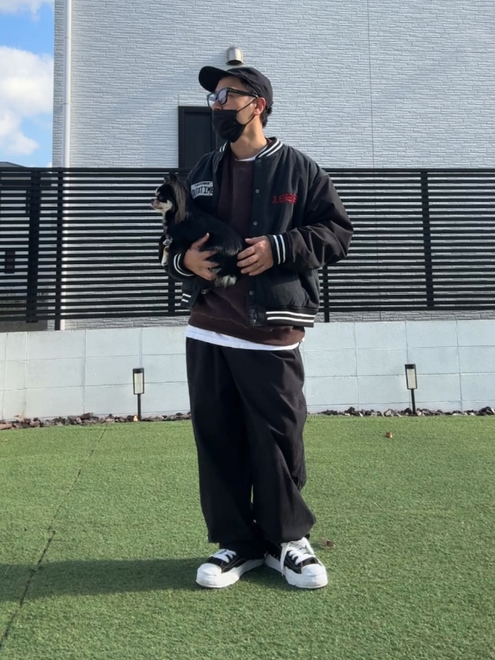 ブラウン系のスウェット、ブラック系のスタジャン、ブラック系のチノパンツを着用したメンズの冬コーディネートの2枚目の写真