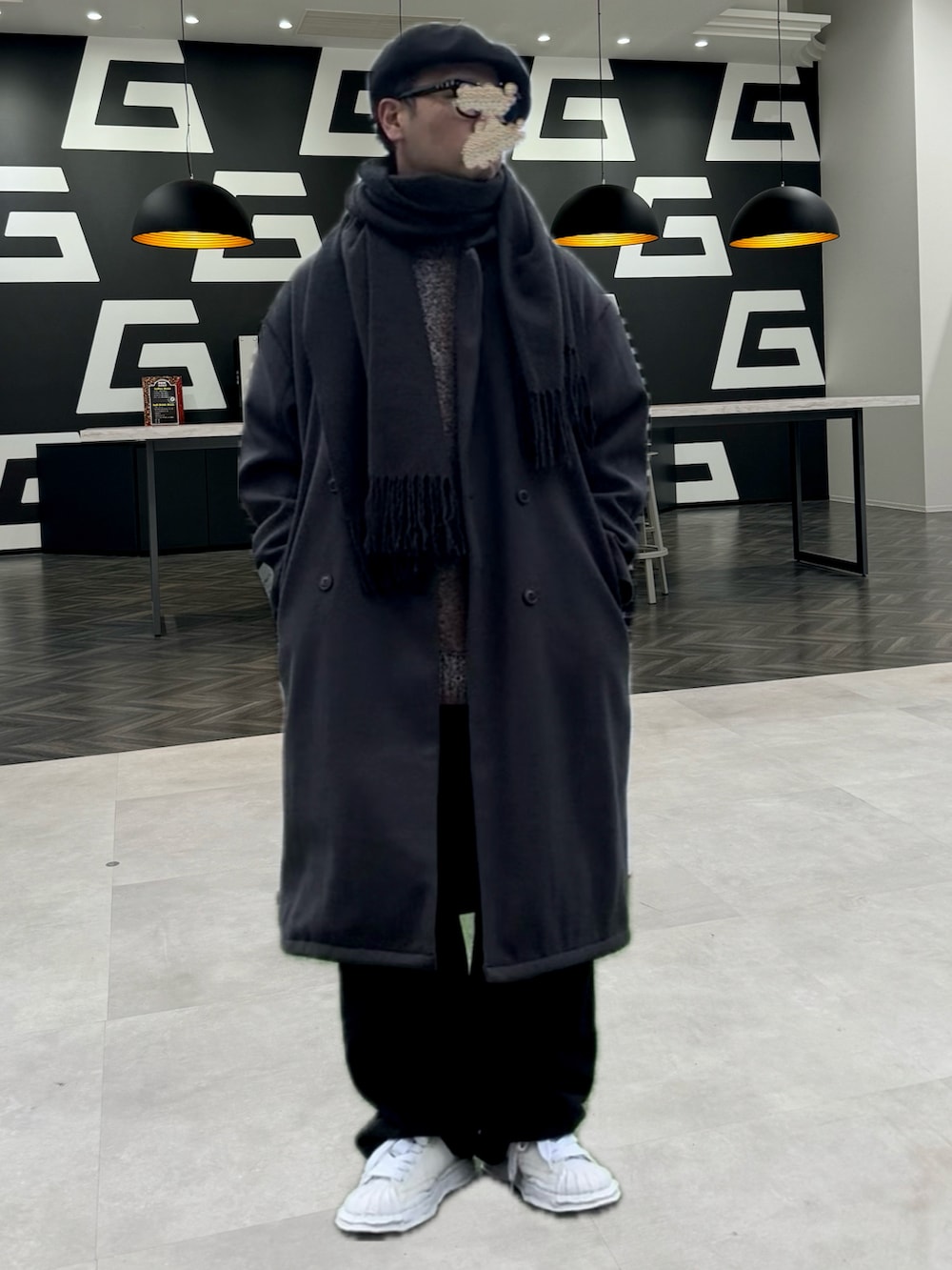 グレー系のチェスターコート、ブラック系のその他パンツ、ホワイト系のスニーカーを着用したメンズの冬コーディネートの2枚目の写真