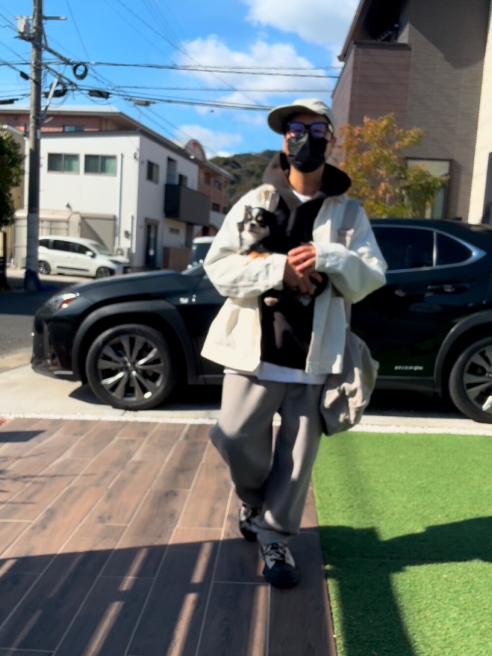 ブラック系のパーカー、ベージュ系のショルダーバッグ、ベージュ系のスラックスを着用したメンズの冬コーディネートの4枚目の写真