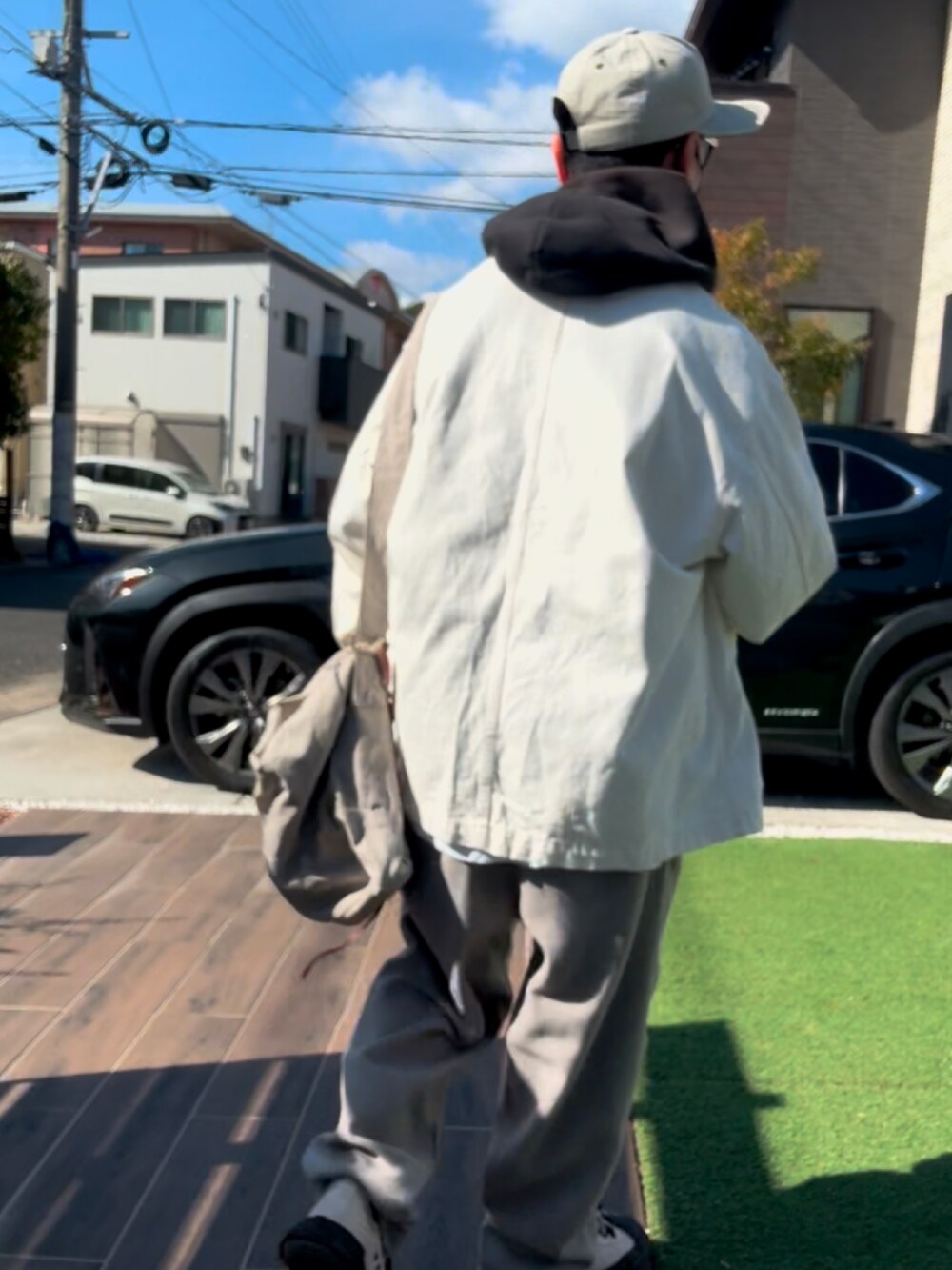ブラック系のパーカー、ベージュ系のショルダーバッグ、ベージュ系のスラックスを着用したメンズの冬コーディネートの5枚目の写真