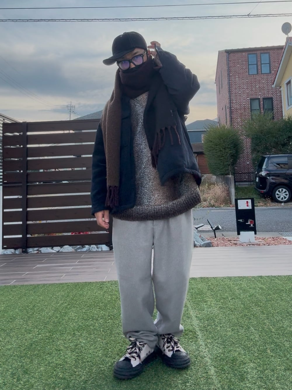 ベージュ系のスラックス、ブラック系のスニーカー、ブラウン系のニット/セーターを着用したメンズの冬コーディネートの3枚目の写真