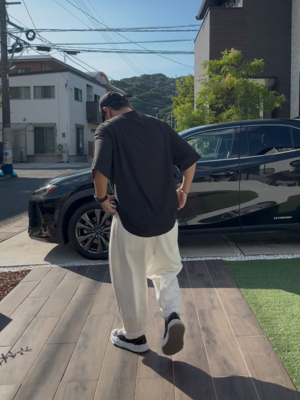 ブラック系のTシャツ/カットソー、ブラック系のスニーカー、ホワイト系のデニムパンツを着用したメンズの秋コーディネートの3枚目の写真